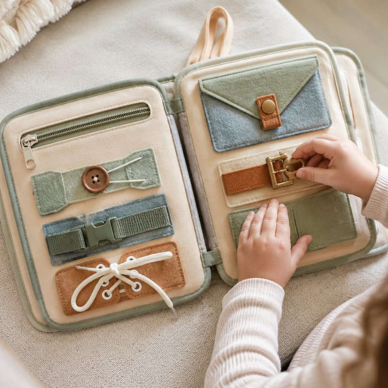 Montessori Life Skills Graduated Busy Book in use — baby playing with cloth book